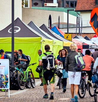 Zeltreihe von 4x4 Faltzelten in Schwarz und Limone mit Ergon-Logo an den Seitenwänden beim Brixen Bike Festival