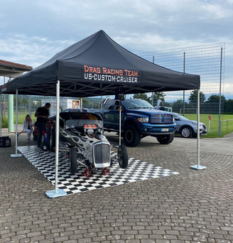 Schwarzer 8x4-Faltpavillon mit Drag Racing Team-Logo bedeckt einen flammenden Oldtimer und wird mit Ecotent-Pavillongewichten am Boden befestigt