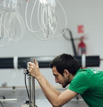 Worker testing material quality with a measuring device in folding gazebo production.
