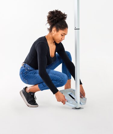 The woman attaches the 10 kg base plate to the folding gazebo.