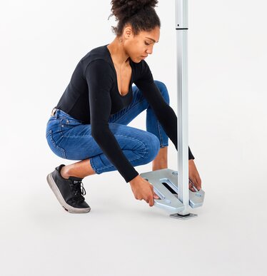 The woman attaches the 10 kg base plate to the folding gazebo.